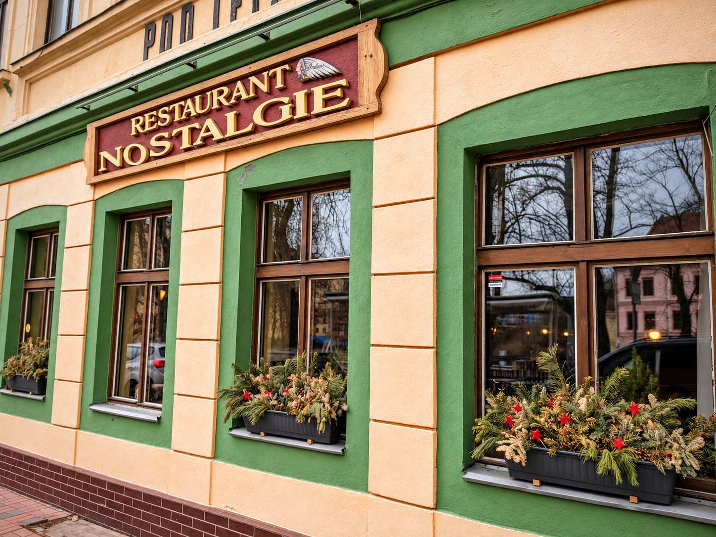 Průčelí restaurace s vínovou cedulí a zelenými okny